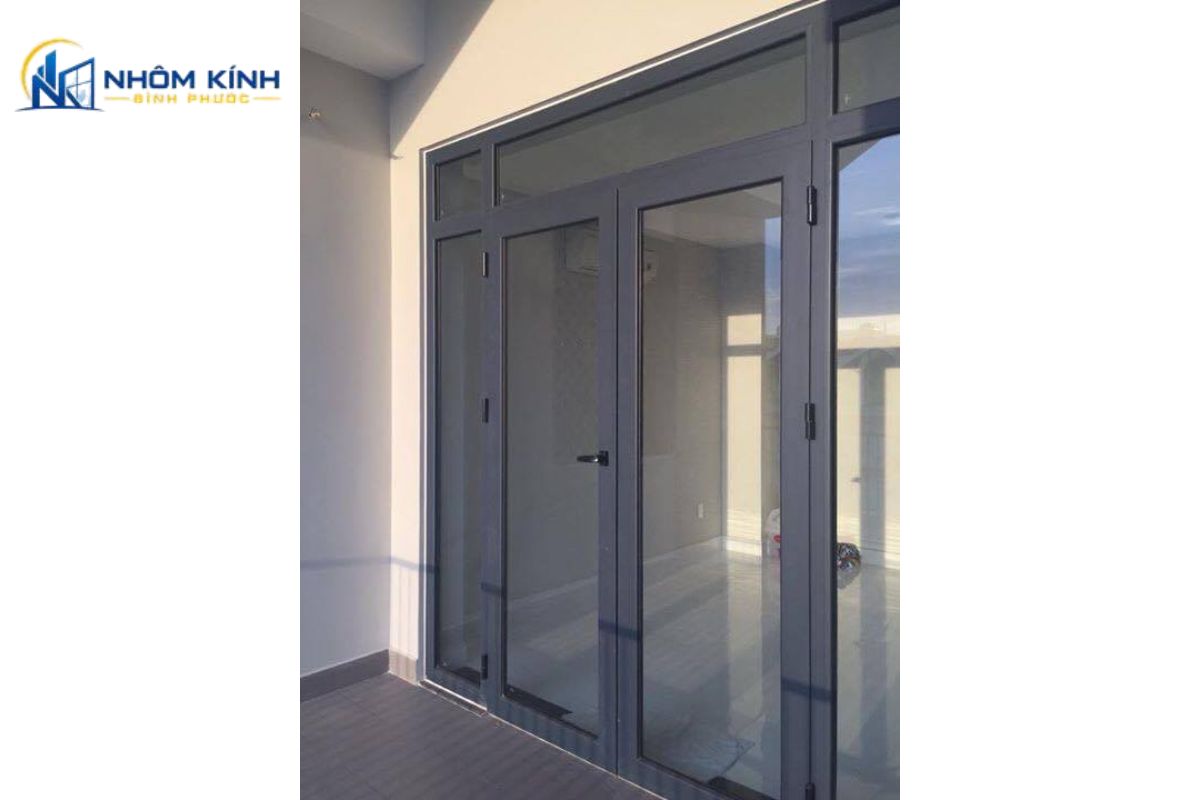 Cửa đi mở quay 2 cánh làm cửa chính nhà phố tạo mặt tiền cân đối, lối vào rộng và dễ phối màu xám ghi hoặc vân gỗ với kiến trúc bên ngoài