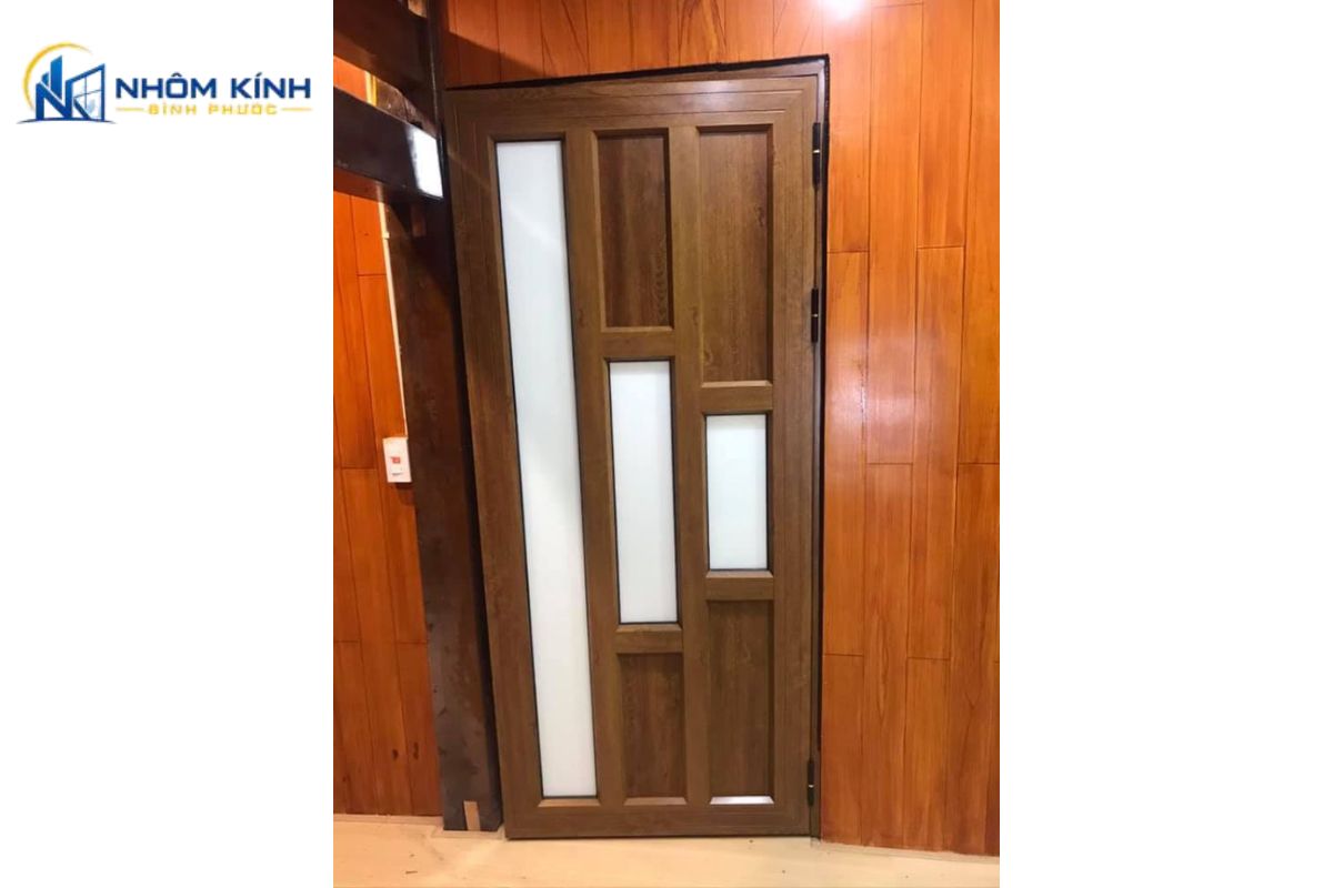 Mẫu cửa nhôm giả gỗ thiết kế pano đặc nguyên khối không dùng kính, mang lại cảm giác chắc chắn, kín đáo và đảm bảo sự riêng tư tuyệt đối cho không gian
